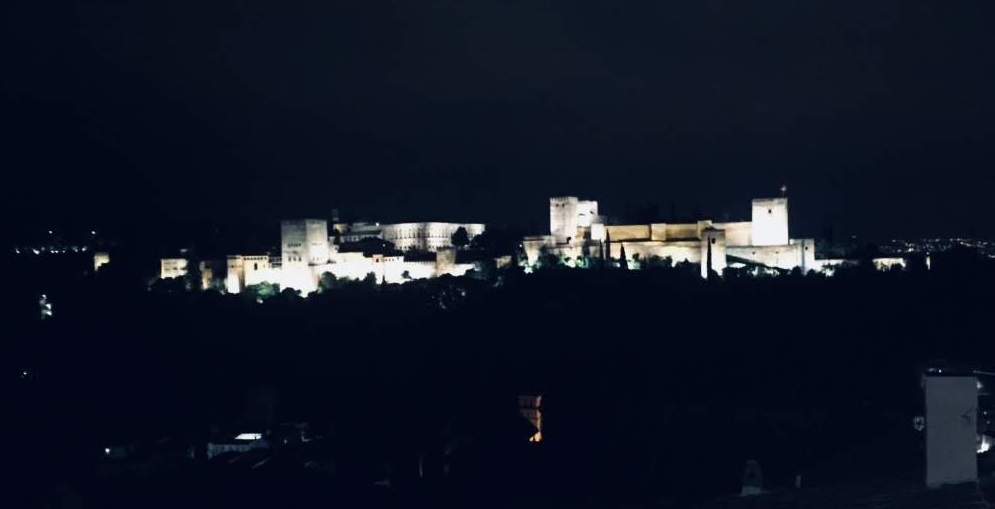 Landscape image of the pale colored la alhambra complex at night, from far away.
